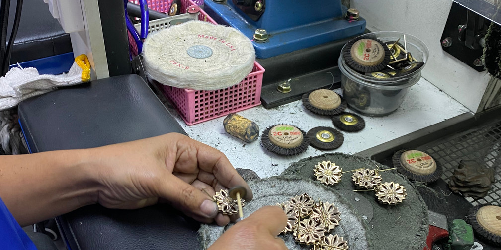 Jewellery pieces being examined at a polishing bench with a motor, wheels and small tools.
