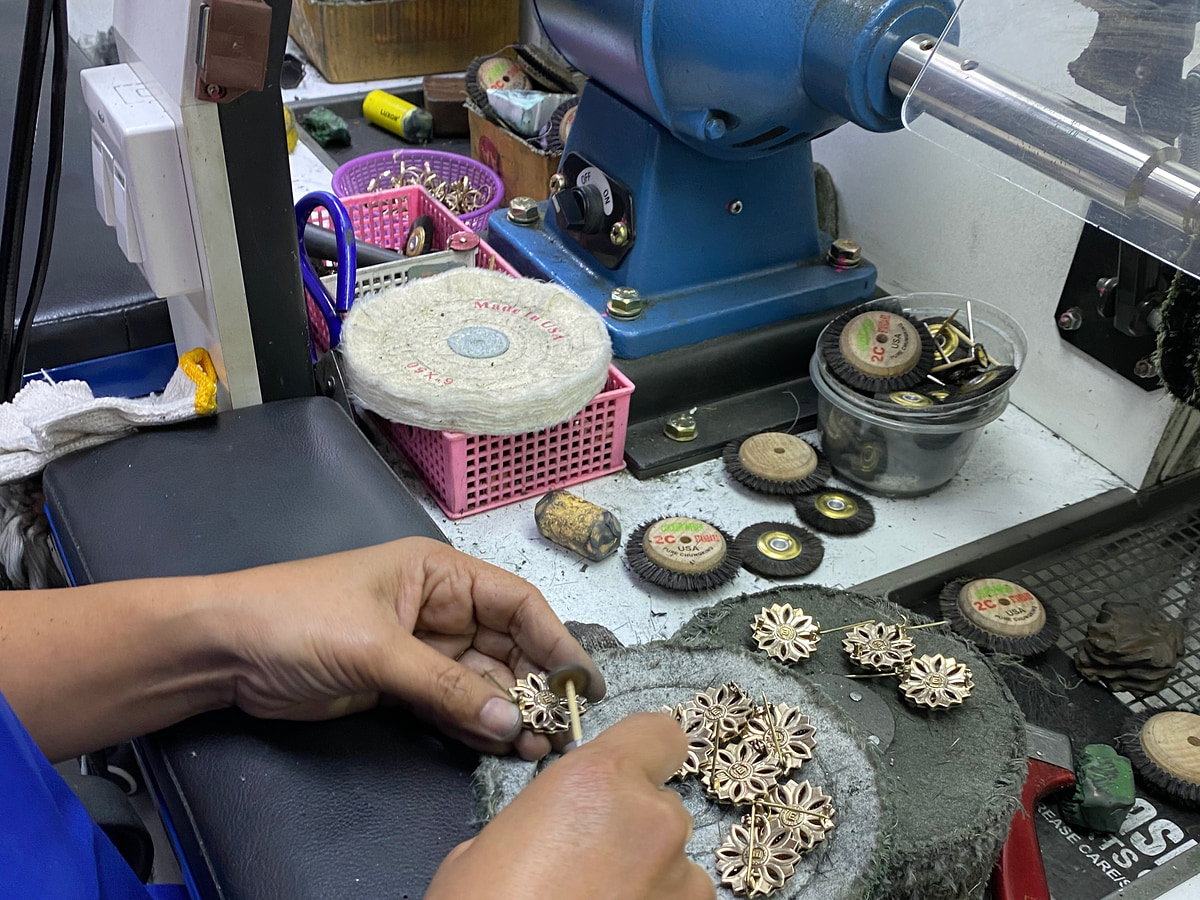 Jewellery pieces being examined at a polishing bench with a motor, wheels and small tools.