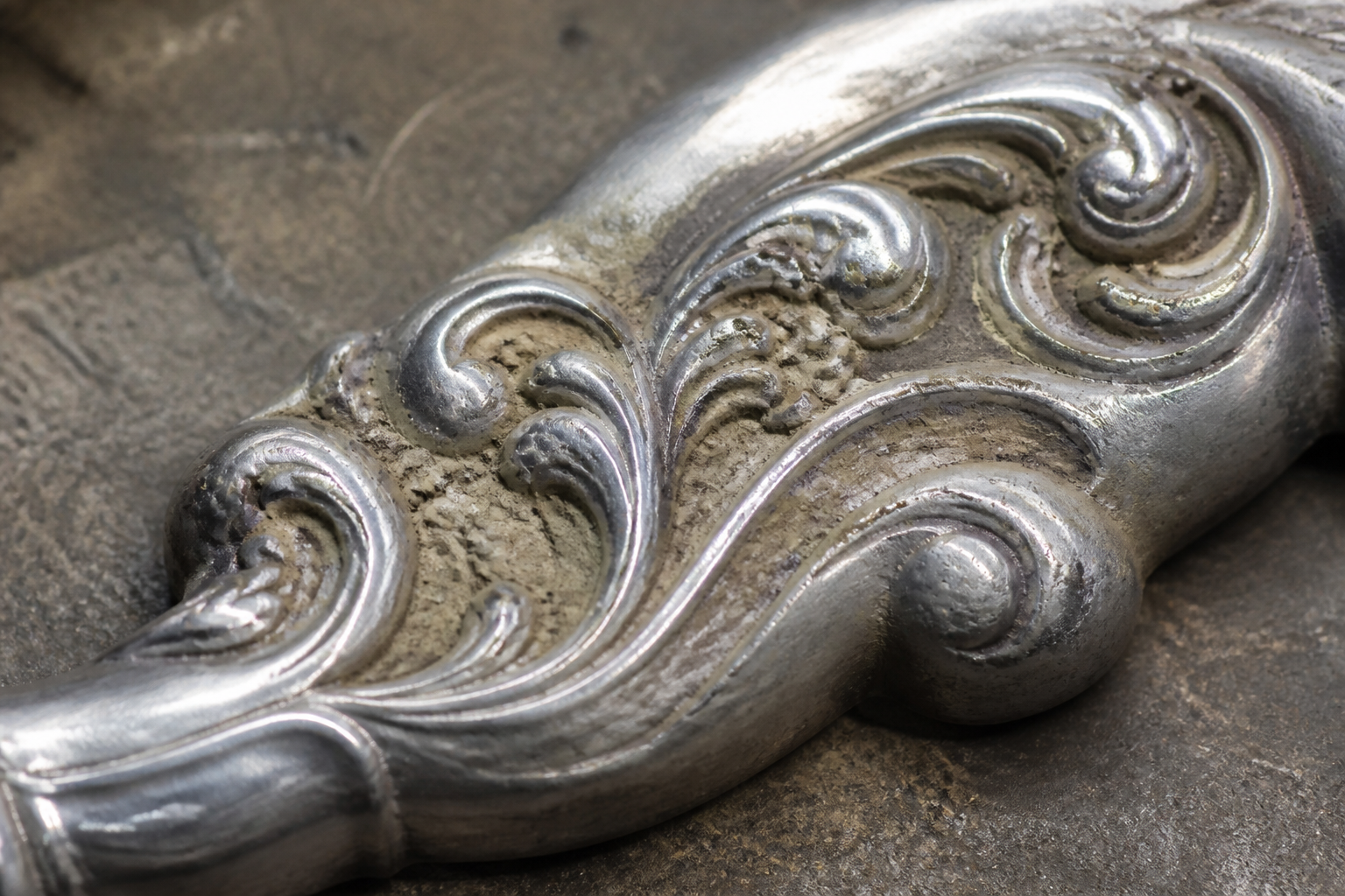 Polishing paste retained in the recessed scrollwork of a decorative metal object.