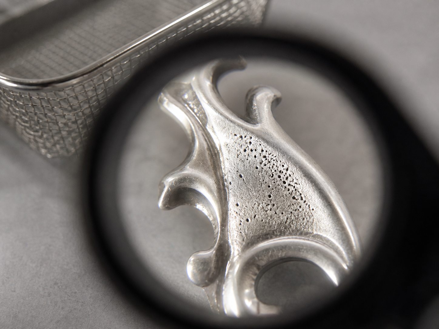 Localized irregular pores visible on a clean metal surface beneath a loupe after cleaning.