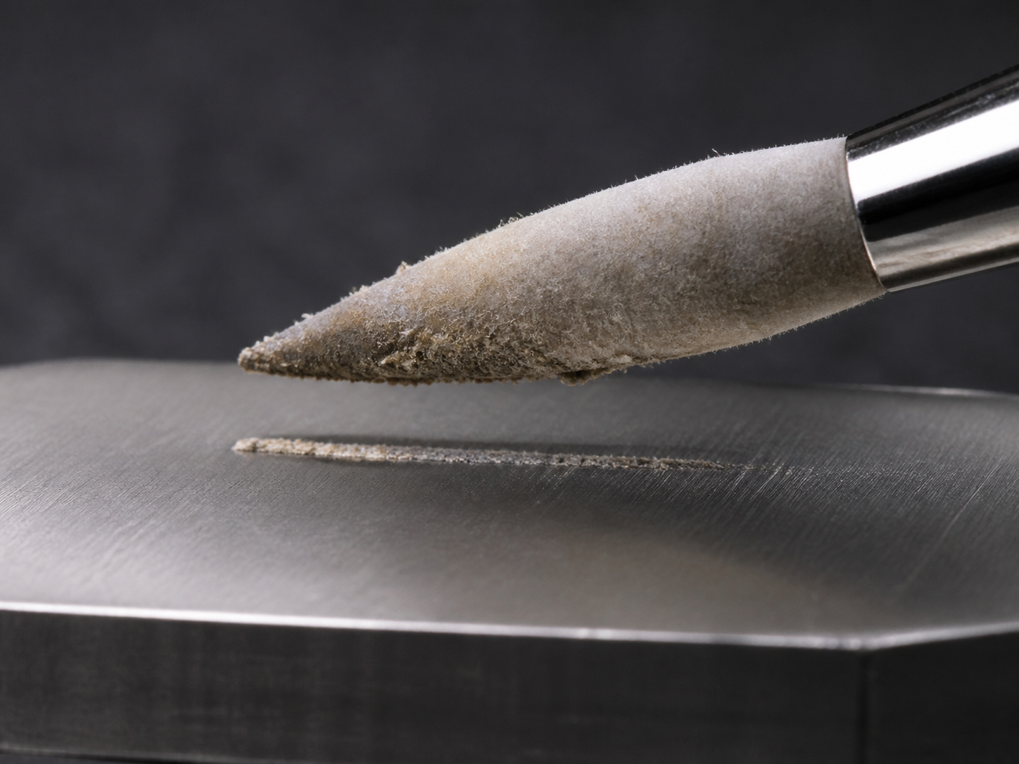 A small tapered felt tool with dry crumbly residue at its working tip and incomplete transfer below.