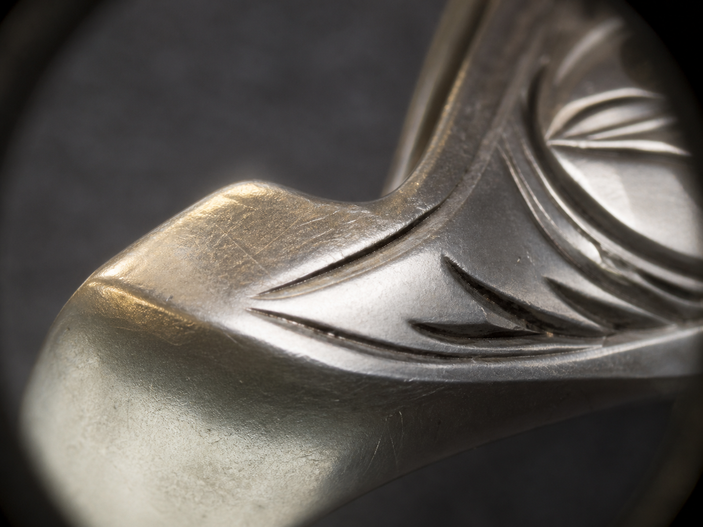 An ornate metal piece with a localized flattened edge beside better-defined engraving.