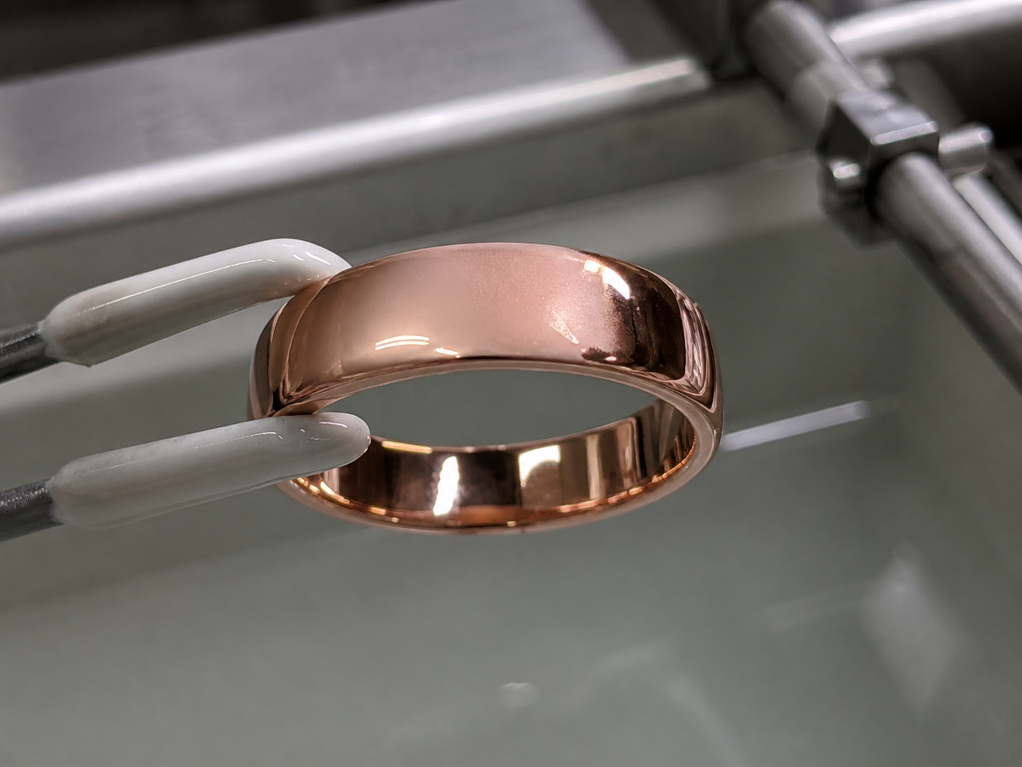 A rose-coloured plated ring with a localized matte haze beside a brighter reflection after bath handling.
